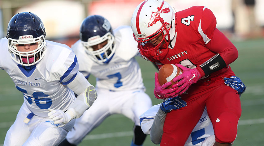 One football player running with the ball and two players running behind him