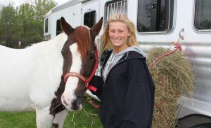 Student smiling while standing next to horse